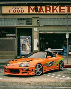 an orange sports car parked in front of a food market