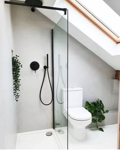 a white toilet sitting next to a shower in a bathroom under a slanted roof