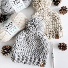 three crocheted hats, one with a pom - pom and the other with pine cones