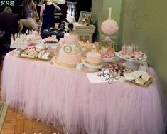 a table topped with lots of cakes and desserts covered in pink tulle skirt