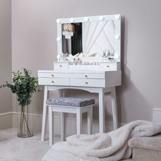 a white vanity table with a stool and mirror