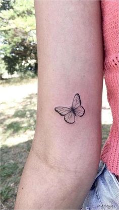 a small butterfly tattoo on the left inner arm, with an outline of a butterfly