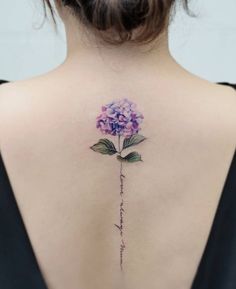 the back of a woman's neck with a flower tattoo on her left shoulder