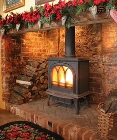 a wood burning stove sitting inside of a living room next to a pile of logs