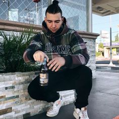 a man sitting on the ground holding a bottle