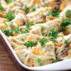 a casserole dish filled with meat and cheese on top of a wooden table