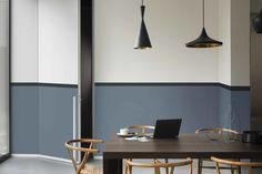 a dining table with two chairs and a laptop on it in front of some hanging lights