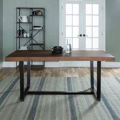 a wooden table sitting on top of a rug in a living room next to a window