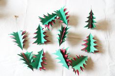 christmas trees made out of green and red paper on a white tablecloth with scissors