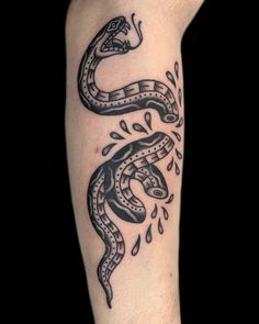 a black and white snake tattoo on the left arm with water droplets coming out of it