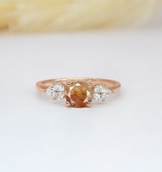 an orange diamond ring with three diamonds on the side, sitting on top of a white surface