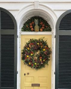 a yellow door with a wreath and pineapples on it