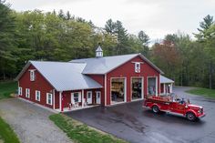 a red truck parked in front of a barn