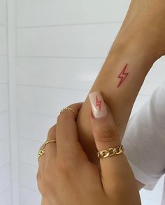 a woman's arm with a lightning tattoo on it and a gold chain around her wrist