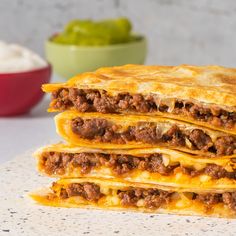 two quesadillas stacked on top of each other next to a bowl of sour cream