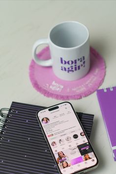 a cell phone sitting on top of a table next to a cup and notebooks