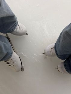 two people wearing white shoes standing next to each other on the snow covered ground with their feet in the air