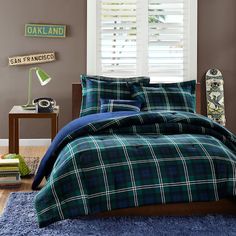 a bed in a bedroom with blue and green plaid comforter set on top of it