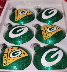 six green bay packers christmas ornaments in a white box with gold and green glitters