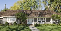 a gray and white house with trees in the background