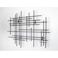 an abstract sculpture made out of black metal rods on a white wall with no one in it