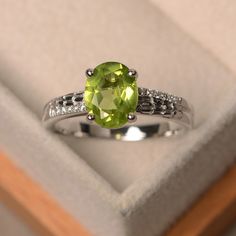 This halo ring features a 7*9mm oval cut real peridot and sterling silver finished with rhodium. Customization is available. It is made by hand, and it will take about 7 days to finish the ring after your payment is completed. Main stone: natural peridot (August birthstone) Peridot weight: Approx 1.99 ct Metal type: sterling silver / 14k gold Accent stone: cz Customization is available, I also can make it with 14k solid gold (white or yellow or rose) and diamond accent stone, just feel free to c Luo Jewelry, Peridot Ring Engagement, Christmas Rings Jewelry, Vintage Engagement Ring Settings, Peridot Engagement Rings, August Birthstone Ring, Green Gemstone Ring, Leaf Engagement Ring, Oval Cut Engagement Ring