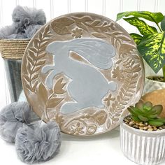 a plate with a rabbit on it sitting next to some plants and other things in front of it