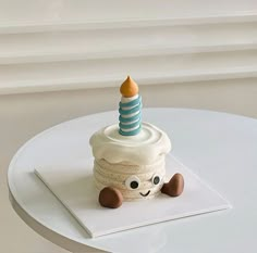 a small cupcake with a candle on top sitting on a white table next to a window