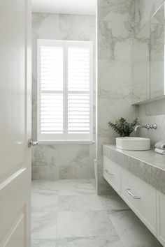 a white bathroom with marble floors and walls