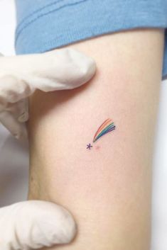 a small rainbow tattoo on the thigh