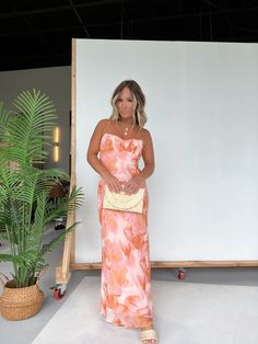 a woman standing in front of a whiteboard wearing an orange and pink floral dress