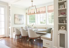 a dinning room table with four chairs and a bench in front of the window