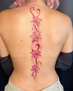 a woman's back tattoo with pink flowers and swirls