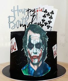 the joker birthday cake is decorated with playing cards and an image of batman's face