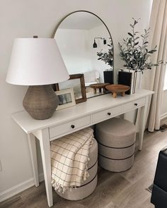 a white table with a mirror, stool and lamp on it in a living room