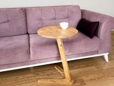 a purple couch sitting next to a wooden table on top of a hard wood floor