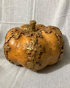 an ornately carved pumpkin sitting on top of a white cloth