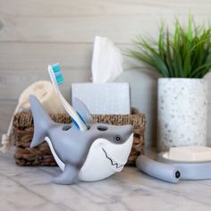 two toothbrush holders are sitting on a counter next to some plants and other items