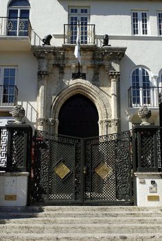 the entrance to an old building with wrought iron gates and stairs leading up to it