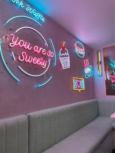 a restaurant with neon signs on the wall and booths in front of it, along with couches