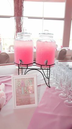 two pink candles sitting on top of a table next to wine glasses and a sign