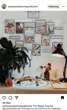 a table topped with pictures and plants next to a lamp