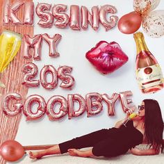 a woman laying on the floor next to balloons and champagne bottles with her feet up