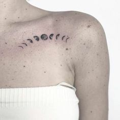 a woman's shoulder with the sun and moon tattoo on it, in black ink