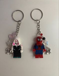 two lego key chains with spider - man and catwoman on them, one is holding the other