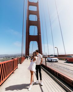 a man and woman standing on the side of a bridge