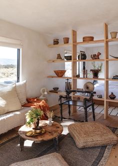 a living room filled with lots of furniture and shelves next to a large open window