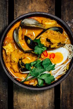 an overhead view of a bowl of soup with clams, noodles and meats