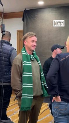 a man wearing a green scarf standing in front of a microphone