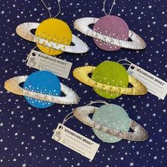 four small ornaments are hanging from strings on a blue tablecloth with white stars in the background